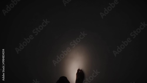 A person holds a glowing orb in their hand in darkness indoors