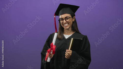 Wallpaper Mural Woman in graduation cap and gown smiles holding rolled diploma tied with red ribbon and a hardcover book in studio; achievement pride. Torontodigital.ca