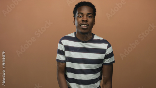 Photos Man flips middle finger at camera in studio while smiling broadly and standing with straight posture; bold defiance