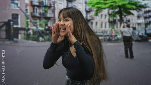 Photography Young woman cupping hand to mouth, calling out with long hair and open palm gesture on street; spontaneous playful