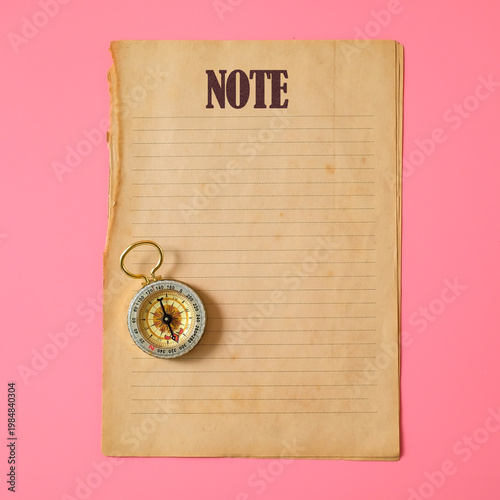 Old paper with vintage compass on color background.