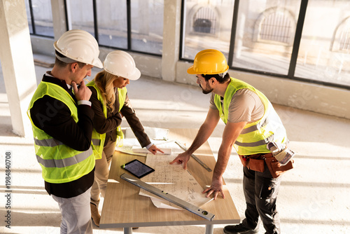 Construction team discusses project plans inside a building under renovation in broad daylight
