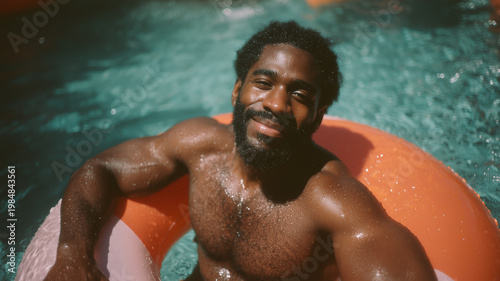A handsome black man with large, hairy pectoral muscles sits on an orange and white inflatable ring in a pool. Ai generated