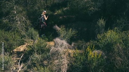 Female hiker walking uphill through a green forest with backpack and trekking poles, symbolizing personal growth, inner strength and mindful journey in nature.