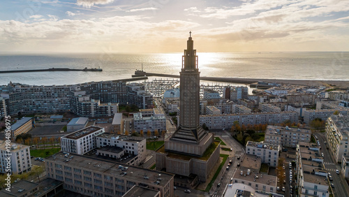 Backlit silhouette of St. Joseph Church tower over shimmering sea water in Le Havre, Normandy, France
