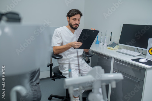 Foto Dark-haired young dentist in his office looking confident and busy