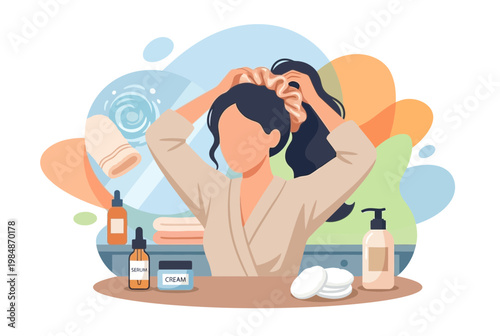 Woman in bathrobe tying hair for skincare routine