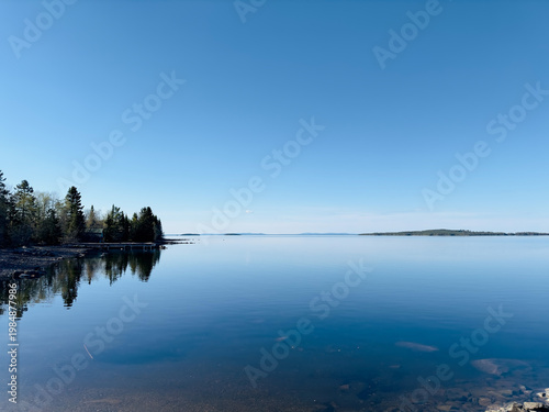 Swedish lake landscape with calm water and distant islands under a clear blue sky