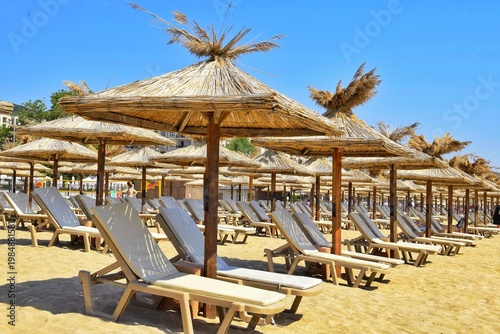 Foto Sun loungers and straw umbrellas on the beach by the sea
