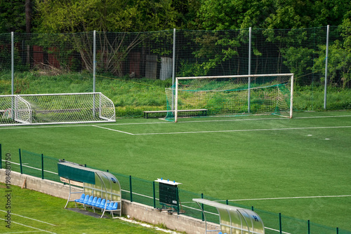 Empty training football field, green trees in background, only one half of playground and goalpost gate visible