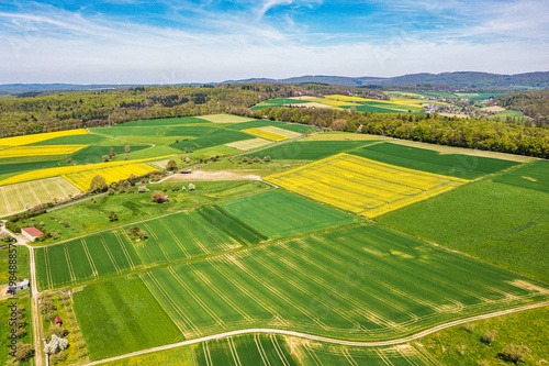 A bird's-eye view of the Taunus landscape awakening in spring, with blossoming trees and yellow rapeseed fields.