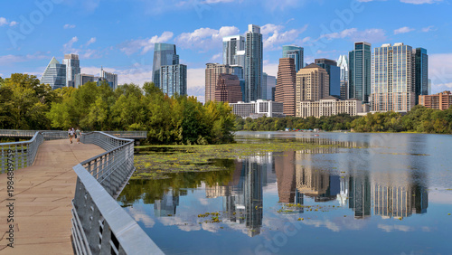 Lake Boardwalk - A panoramic view of the boardwalk of Ann and Roy Butler Hike-and-Bike Trail at Lady Bird Lake, with modern skyscrapers towering in background, on a sunny Autumn day. Austin, Texas, US