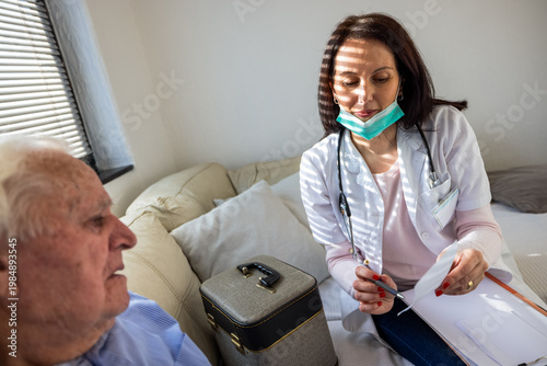 Принти на полотні Elderly man taking prescribed medicine under the supervision of a female physician at home