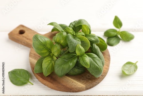 Fresh basil leaves on white wooden table, closeup