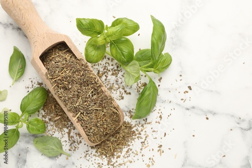 Dry basil, scoop and fresh leaves on white marble table, flat lay. Space for text