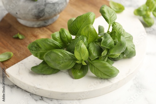 Fresh basil leaves on white marble table, closeup