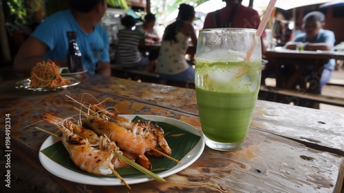 Grilled shrimp on a plate, green drink, and people dining at a rustic wooden table
