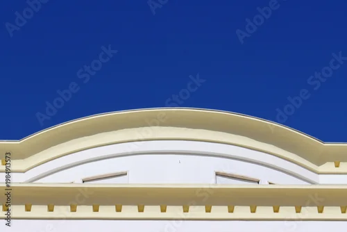 Obraz Elegant architectural detail with a curved classical facade against a clear deep blue sky, ideal for urban design, travel themes, and building exterior concepts.