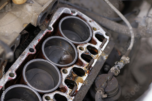 Foto Four-cylinder engine block with removed cylinder head showing pistons, fluid contamination, and gasket residue, indicating maintenance and repair