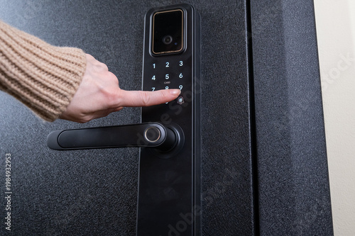 Cuadro en lienzo A woman opens a modern smart door lock with a digital keypad using a code