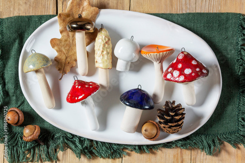 Ceramic mushrooms, pine cones, and acorns on a ceramic plate and wooden tabletop.