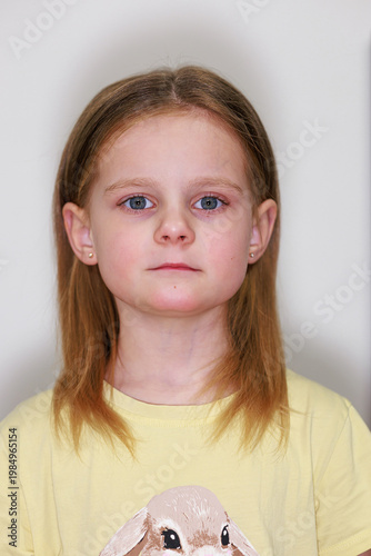 Studio portrait of a serious young blonde girl wearing a yellow shirt