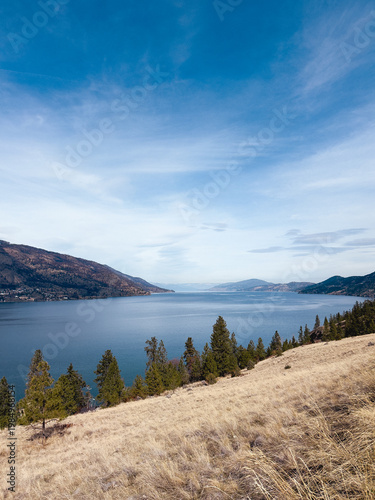 View of calm lake Okanagan surrounded by mountains under a blue sky