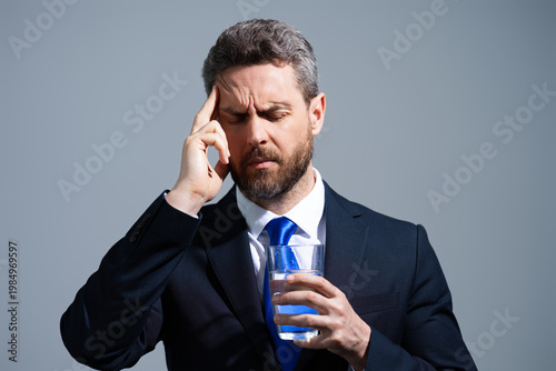 Man with headache on isolated gray studio background. Man feel pain rubbing dry eyes fatigued from work. Stressed man suffer from headache bad vision sight problem. Deadline and stressed job.