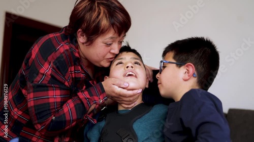 Happy latin american mother kissing her diverse children at home - Family love and disability care concept