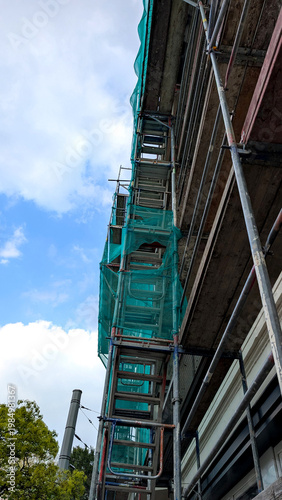 Metal scaffolding on a gray building facade during renovation. Exterior construction work, maintenance and restoration concept. 