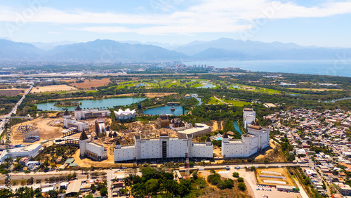 Aerial view of an elaborate castle-like structure nestled amidst a vibrant landscape of green fields and winding waterways, Riviera Nayarit, Mexico