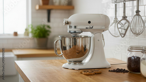 White stand mixer sitting on a clean wooden countertop in a bright modern kitchen. culinary equipment, domestic cooking, interior design.