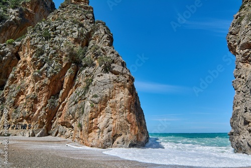 Scenic coastal canyon opening to a wild beach with white sea foam. Iconic natural landmark for Mediterranean vacation advertising and travel brochures Spectacular European seaside landscape Copy space