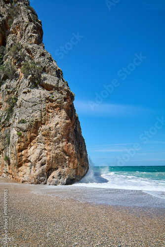 Scenic coastal canyon wall on a wild pebble beach with turquoise sea water. Iconic natural landmark for Mediterranean tourism marketing and vacation brochures. Spectacular seaside landscape Copy space