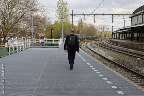 Person walking along railway platform at Haarlem station. The image shows daily commuting and urban lifestyle.