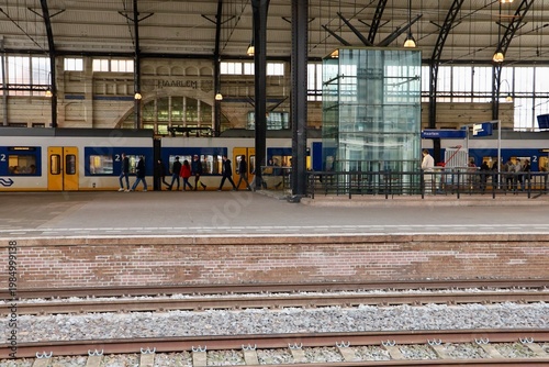 Interior of Haarlem railway station with glass structure and passengers. The architecture combines modern elements with historic design.
