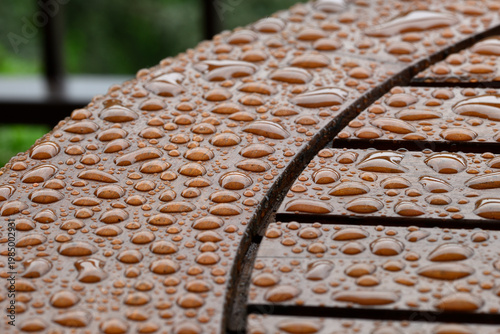 Close-up of rain droplets on a wet wooden table surface