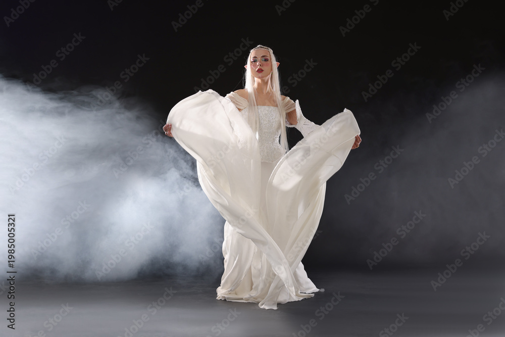 Fototapeta premium Beautiful girl dressed as elf on black background with smoke
