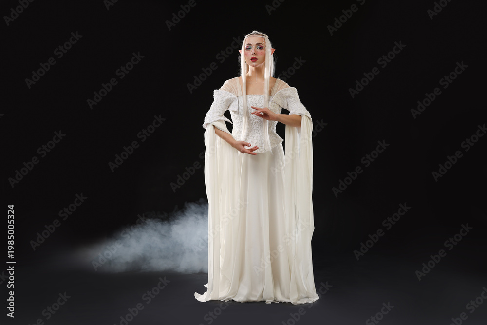 Fototapeta premium Beautiful girl dressed as elf on black background with smoke
