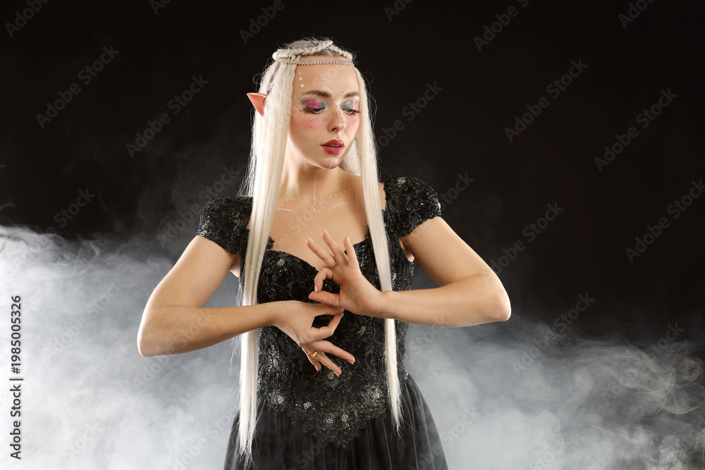 Fototapeta premium Beautiful girl dressed as elf on black background with smoke