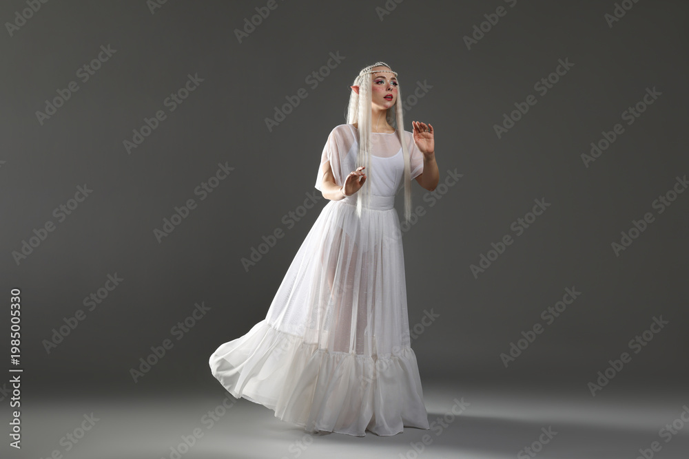 Fototapeta premium Beautiful girl dressed as elf on grey background