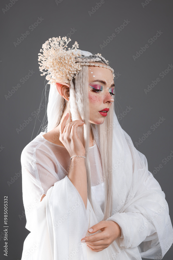 Fototapeta premium Beautiful girl dressed as elf on grey background