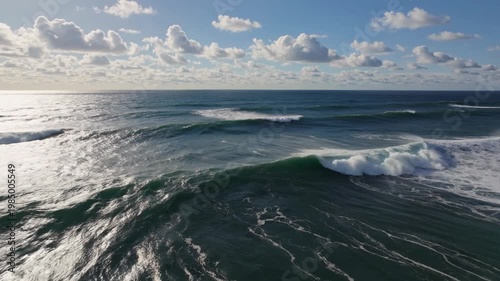Vast Midday Ocean Beneath Bright White Clouds With Dynamic Swells and Shimmering Reflections Below