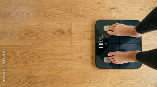 A person stands on a digital scale without socks at home. The scale shows a weight reading in pounds on a wooden floor. This scene captures a moment of weighing oneself indoors