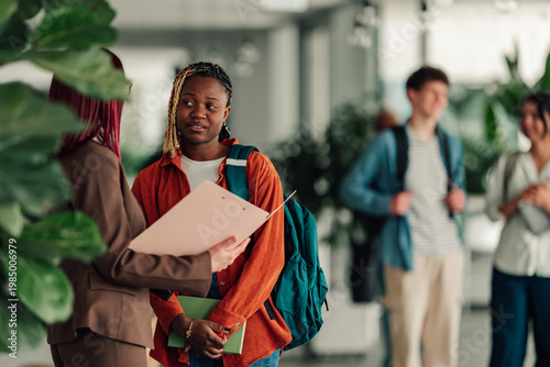 Student receiving guidance from professor, discussing academic progress and future education plans in university setting