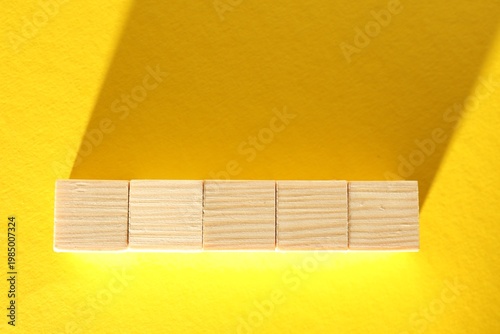 Blank wooden cubes on yellow background, flat lay. Space for text