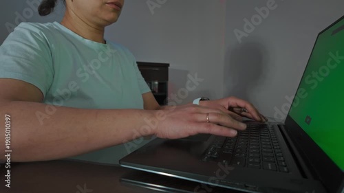 Focused Woman Types on Laptop with Green Screen, Ideal for Digital Content and Remote Work