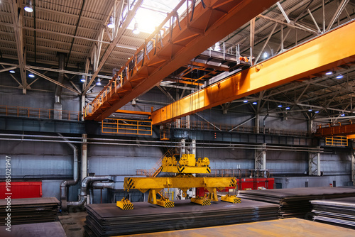 фотографія Overhead crane with magnetic grippers lifting steel sheets in metalworking facto