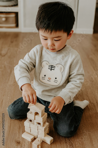 Adorable toddler engrossed in building a tower with wooden blocks.