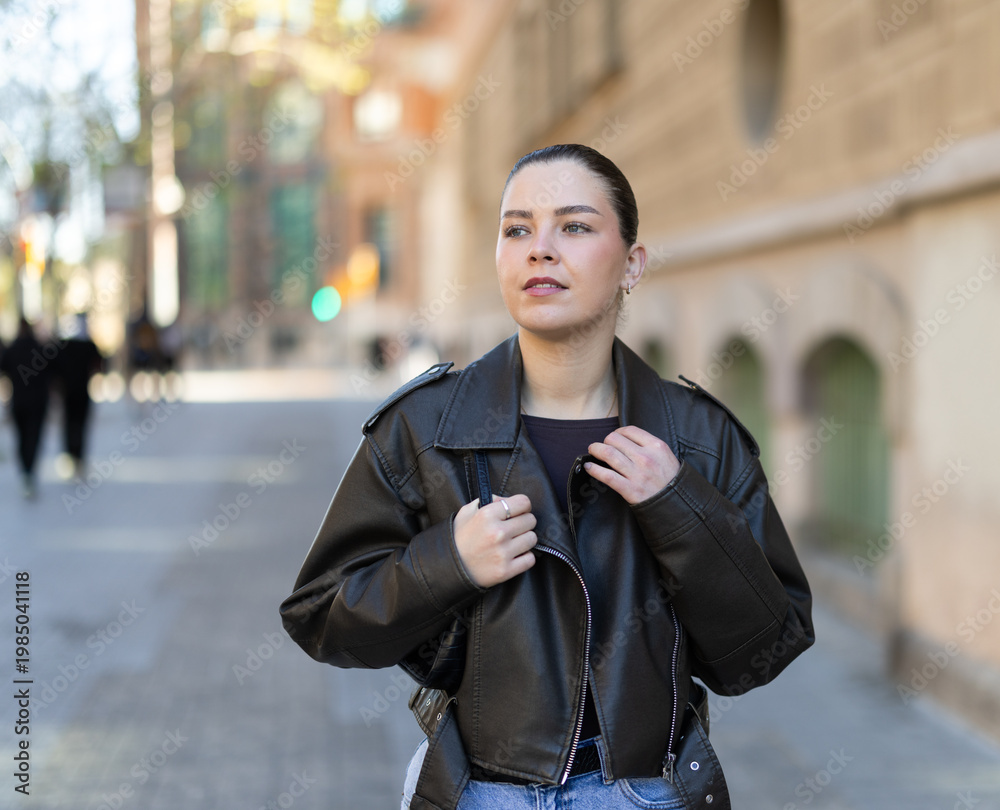 Obraz premium Young woman walks along city street on summer day